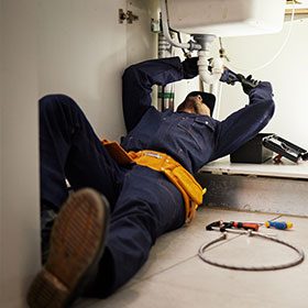 plumber working under the sink
